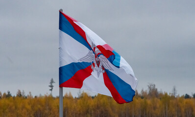 The flag of the Ministry of Defense of the Russian Federation is flying in the wind against a cloudy sky.