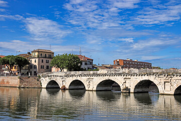 Fototapeta na wymiar Old stone Tiberius bridge and buildings in Rimini Italy