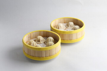 handmade steamed Shanghai Xiao long bao pork meat mini dumpling soup in bamboo basket on white...