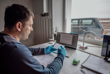 person wearing gloves works on a laptop, signifying a high-tech or research-driven environment