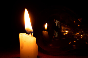 Incandescent lamp and candle in the dark at home