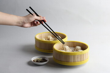 handmade steamed Shanghai Xiao long bao pork meat mini dumpling soup in bamboo basket on white table fast food asian snack dim sum halal food appetiser hotel restaurant banquet cuisine cafe menu
