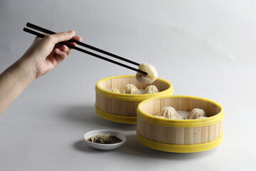 handmade steamed Shanghai Xiao long bao pork meat mini dumpling soup in bamboo basket on white...