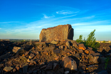 A huge stone from the depths of an iron ore quarry in the rays of the setting sun