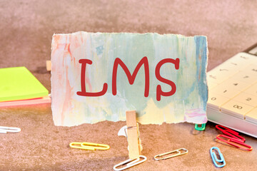 Word cloud concept. LMS - Learning Management System acronym written on paper in a clothespin