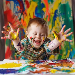 Fotobehang a boy with Down syndrome enthusiastically painting with their hands © ramona