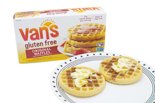 Ocala, Florida 4-25-24 box of Vans gluten free original waffles baked with whole grain brown rice on an isolated background. Two waffles with butter and maple syrup on a white plate with edge design