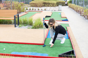 Woman playing mini golf at course. Summer sport and leisure activity