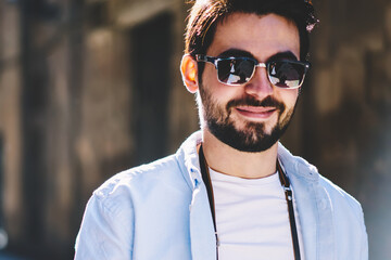 Cropped portrait of cheerful handsome bearded tourist smilin at camera while walking...