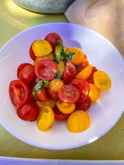 Red and yellow  tomatos on the white bowl.