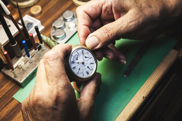 The hands of a watchmaker making the final adjustments to the repaired watch.