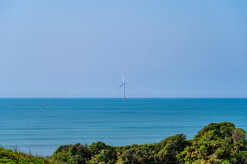 海に立つ風力発電とヨット
