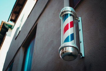A barber pole hung on the wall of a building facade