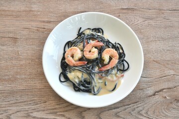 black squid ink spaghetti with shrimp dressing white carbonara cream sauce on plate 