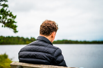 young man sitting on the bench overlooking the lake in estonia lahemaa national park