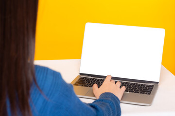 Woman Working on Laptop with Blank Screen,Rear view of a woman using a laptop with a mock-up screen against a vibrant yellow background.
