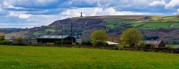 Panoramic image of green fields and peel tower at the top of the hill in Ramsbottom, Greater Manchester. 