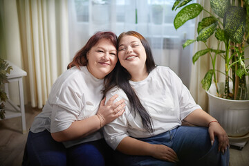 Happy Overweight family with mother and daughter in room. Middle aged woman and teenager girl...