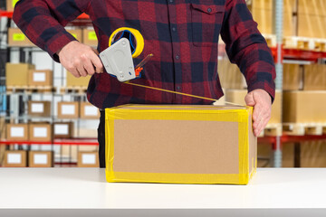 Man will pack box. Packer guy uses dispenser with tape. Packing parcel at warehouse. Cropped packer...