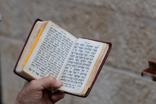 Closeup of a woman's hand holding a siddur or Jewish prayer book during services at the Western Wall in Jerusalem.