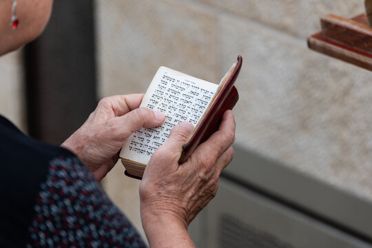 Closeup of a woman's hands holding an open siddur or Jewish prayer book during services at the Western Wall in Jerusalem.
