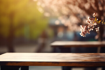 Empty wooden table with cherry blossom flower and copy space for product display. Spring beautiful with flowering branches and blurry foliage in the background.