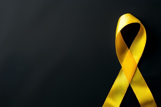 Yellow ribbon on textile background with copy space for endometriosis awareness month or sign for microencephaly and suicide prevention.