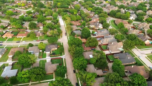 Flyover upscale residential neighborhood in Dallas Fort Worth metro complex, large suburban single-family homes, fenced backyard, swimming pool, quiet tree lined streets, lush green subdivision