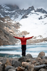 Hombre feliz festejando de haber llegado a la laguna de los tres, al pie del cerro Fitz Roy, recorrido de senderismo en el Chalten, Patagonia Argentina