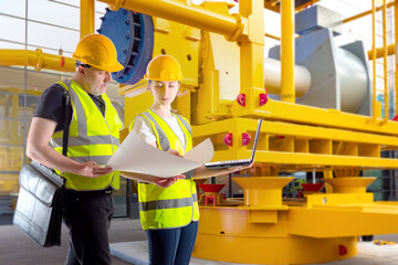 Teamwork factory employees. Man and woman near industrial equipment. Two engineers discuss...