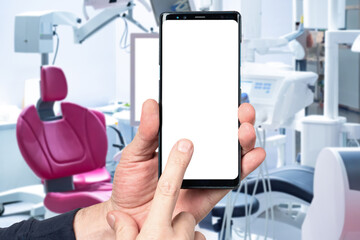 Dental office. Phone with white screen. Equipment for dental treatment. Smartphone in hands. Dental...