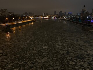 Winter city ​​view from the bridge to the river with ice