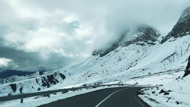 Ceylomsky pass from a car window in Ingushetia. A trip uphill to the Tsei Loam pass on a cloudy spring day. Panorama of the high cliffs of the Dzheyrakh gorge. North Caucasus, Russia. 4K