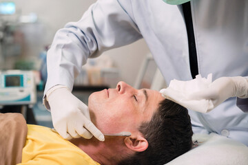 surgery person remove caucasian man moisturizer on face. male patient after facial treatment got...