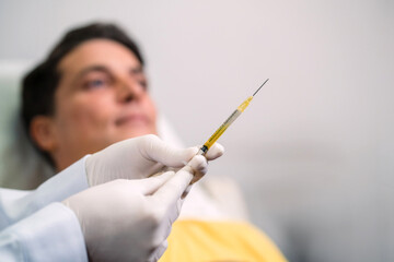 surgery doctor holding up medical syringe. surgeon staff preparing therapy operation lifting needle...