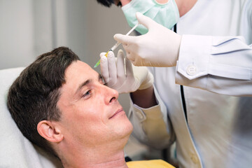 clinic person injecting caucasian man rejuvenate face skin. handsome patient got facial treatment...