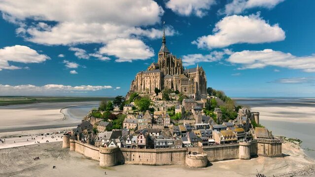 Aerial view of the famous French landmark Abbaye du Mont-Saint-Michel at brighter day with beautiful white clouds. Normandie. France.
