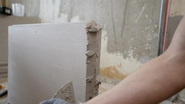 Partition made of tongue-and-groove slabs. A mason applies cement adhesive to a brick when constructing an interior wall.