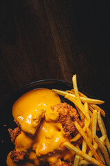 top view of crispy chicken bits with cheddar sauce and french fries