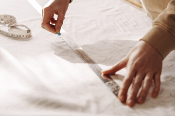 Close-up of hands measuring fabric with ruler and tape measure