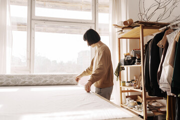 Focused craftswoman, arranging fabric in her sunny workshop.