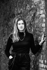 Portrait of a young beautiful girl in dark clothes. Black and white photo.