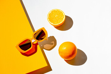 Minimal style composition made of trendy sunglasses and orange fruit on sunlit geometric background