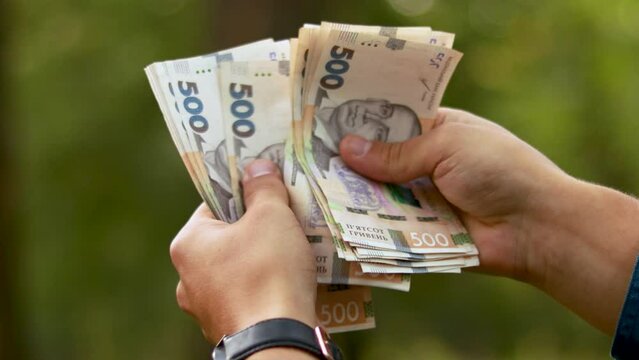 Close up man hands counting money before a big purchase. Ukrainian currency in denominations of 500 hryvnia banknotes bills UAH finance. Money of Ukraine
