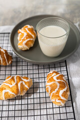 overhead view of some croissants and glass of milk on a plate on a cooling rack on gray background