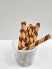 Crispy chocolate cream-filled rolled wafer sticks in a transparent container