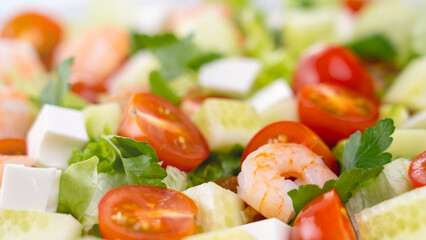Salad in a Greek shrimp salad. A close-up salad of fresh vegetables, a plate of fresh salad with vegetables and herbs. The concept of a delicious and healthy dish. Greek salad with juicy tomatoes.