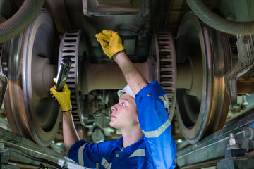 Maintenance Worker Examining Train Wheels with Torch