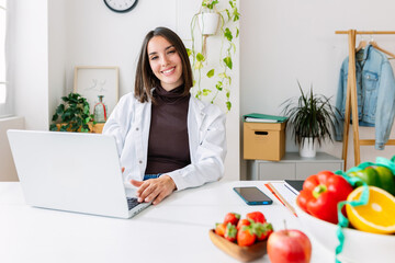 Smiling dietitian woman looking at camera sitting at hospital workplace. Nutrition, diet and professional healthcare worker concept