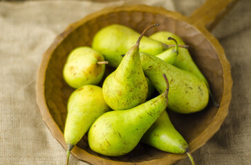 pears on a wooden table in a wooden bowl
